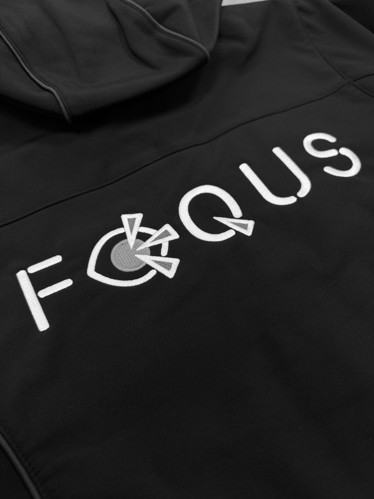 Focus logo geborduurd op de rug van een donkerblauwe softshell met capuchon