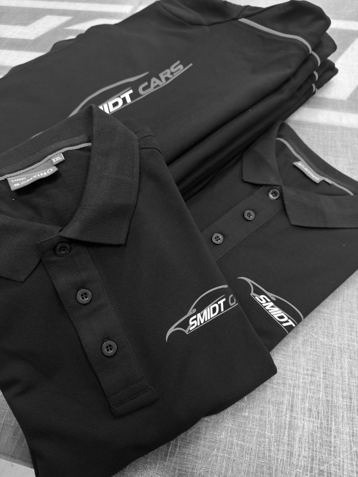 Smidt Cars logo bedrukt op zwarte Santino polo's in oranje en wit