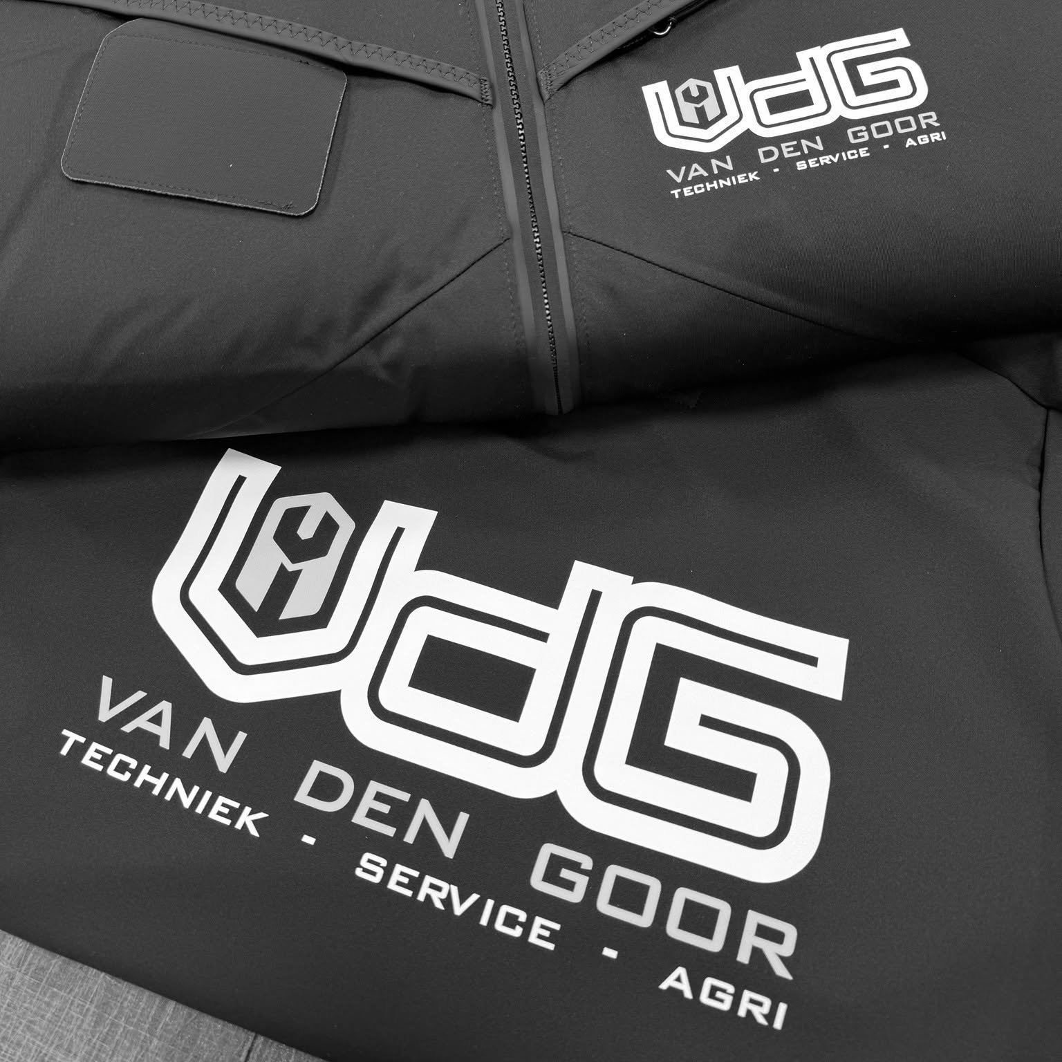 Van den Goor logo bedrukt op werkjas en softshell, in wit en geel